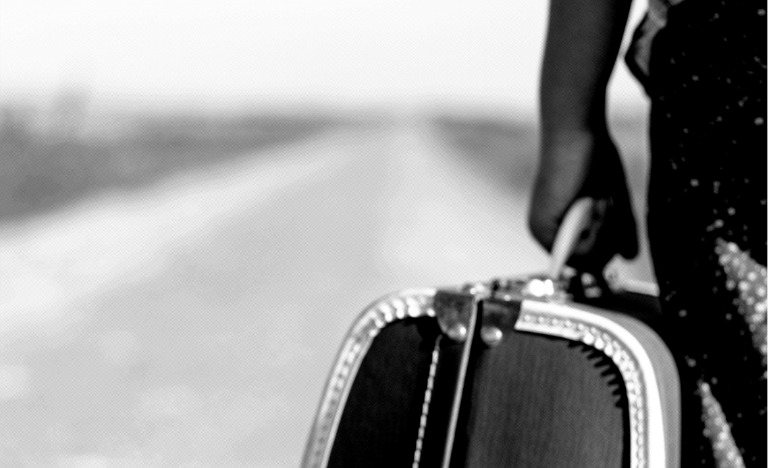 Child with suitcase on long empty road