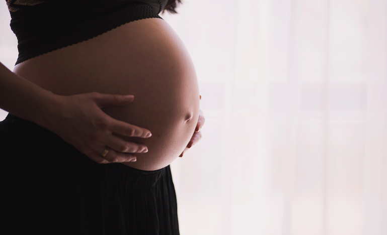 Pregnant lady with her hands around her stomach