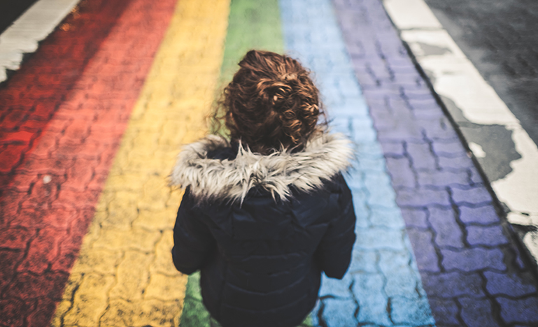 Little girl standing on rainbow painted street