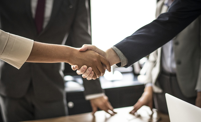 Handshake between business woman and business man to illustrate parties agreeing