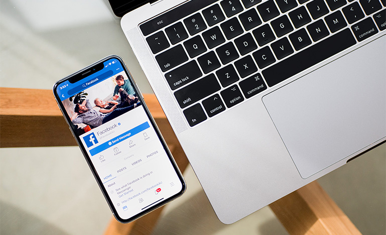 Smartphone with Facebook on the screen beside a laptop