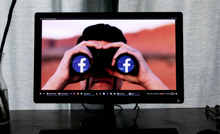 Man with binoculars with Facebook logo in the lenses