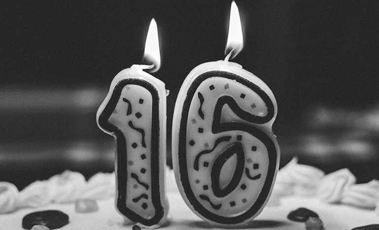 Lit candle in the shape of '16'