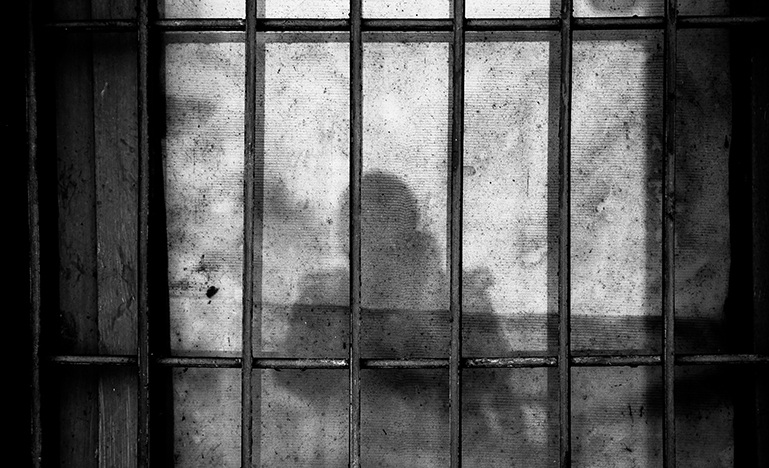 Shadow of person behind bars in prison